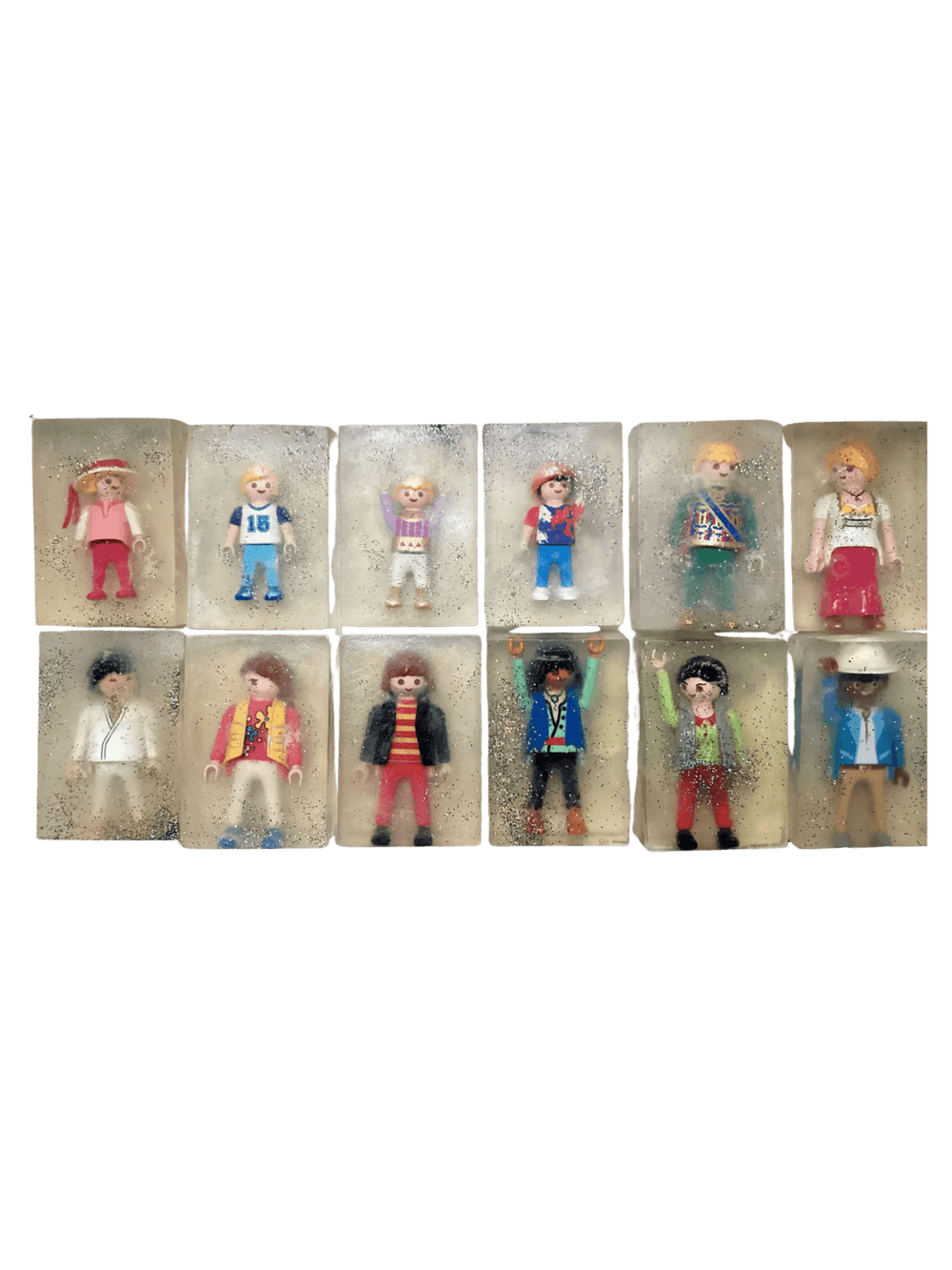 Individual bars of Cavancha Magic Glitter Soap Adults - Playmo arranged in a grid, with each clear, sparkly soap embedding a unique plastic toy figure | Twentyseven Toronto