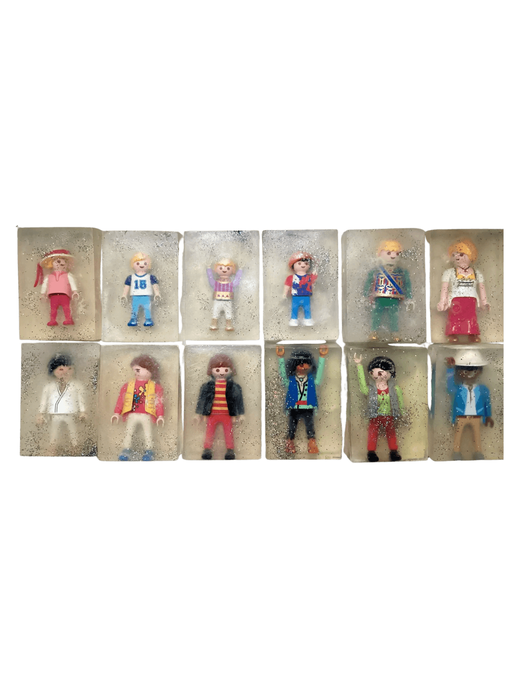Individual bars of Cavancha Magic Glitter Soap Adults - Playmo arranged in a grid, with each clear, sparkly soap embedding a unique plastic toy figure | Twentyseven Toronto