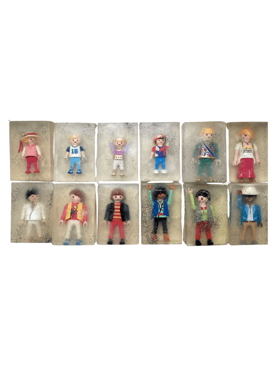 Individual bars of Cavancha Magic Glitter Soap Adults - Playmo arranged in a grid, with each clear, sparkly soap embedding a unique plastic toy figure | Twentyseven Toronto
