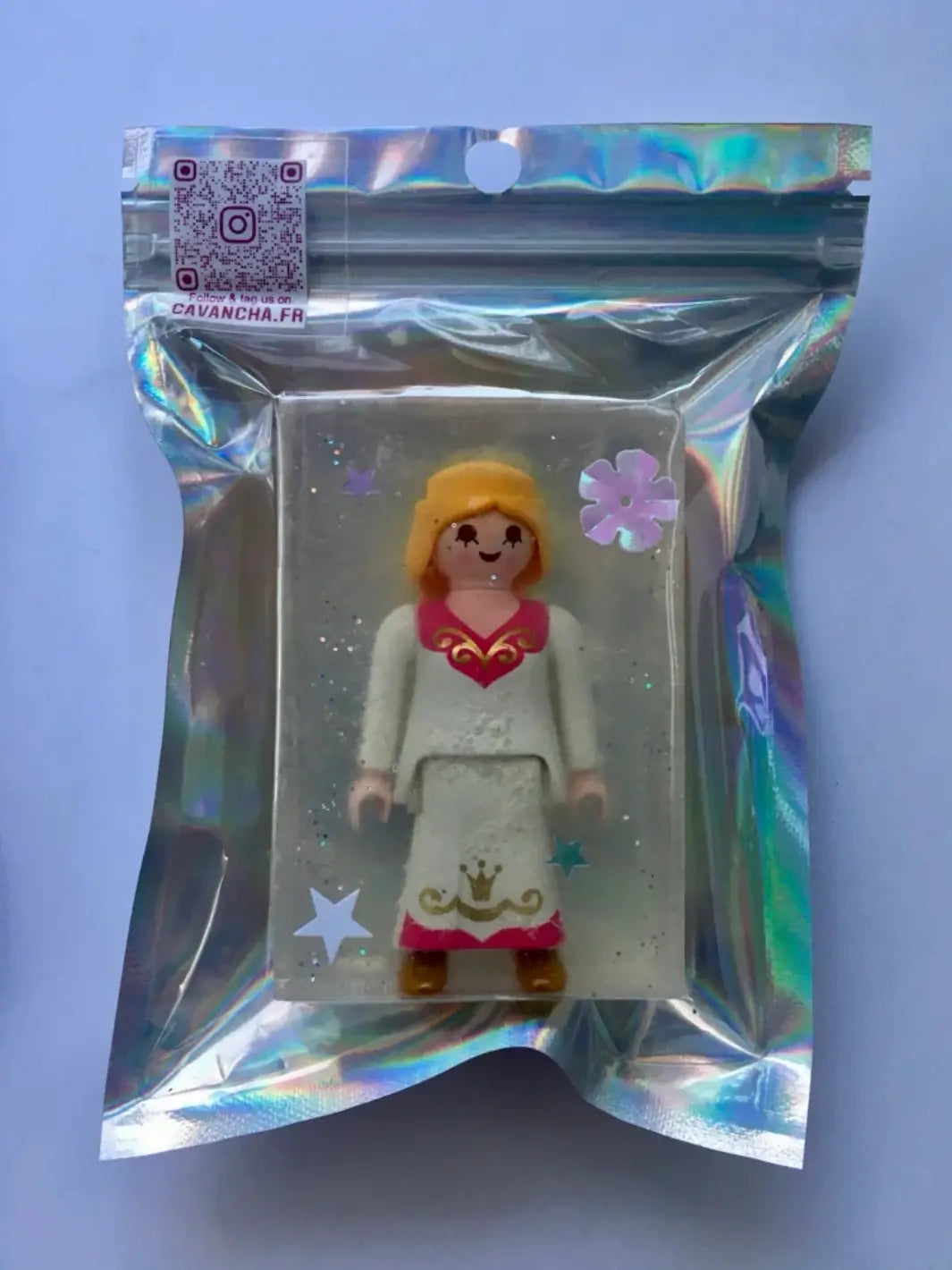 A single bar of transparent Cavancha Magic Glitter Soap Adults - Playmo featuring an embedded female toy figure, sealed inside a shiny, holographic zip-top bag | Twentyseven Toronto