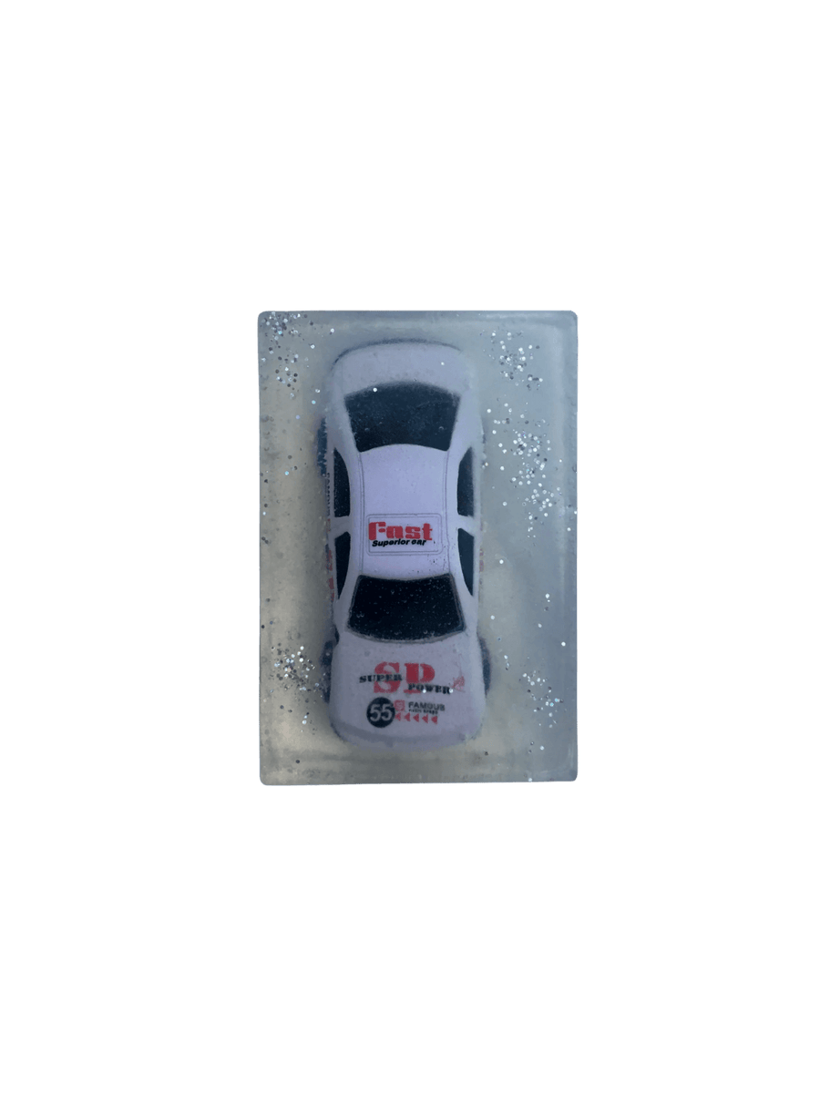 A rectangular bar of clear Cavancha Magic Glitter Soap - Cars embedded with a white toy race car and surrounded by silver glitter sparkles against a transparent background | Twentyseven Toronto