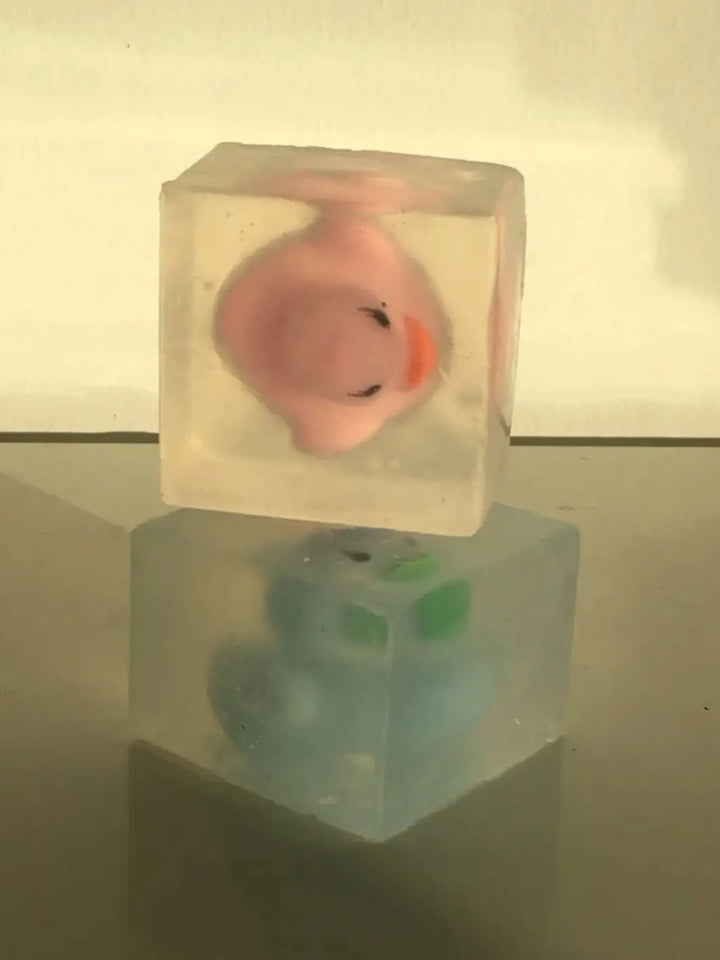 Two transparent, cube-shaped bars of Cavancha Magic Glitter Soap - Ducky are stacked vertically, with a pink duck toy in the top bar and a blue duck toy visible in the bottom bar | Twentyseven Toronto