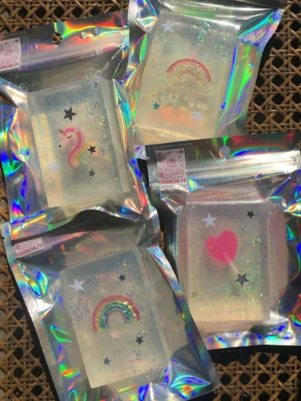 Four individually packaged bars of Cavancha Magic Glitter Soap - Fairy Tales displaying different embedded designs like rainbows, a unicorn, and a pink heart wand are grouped together on a woven surface | Twentyseven Toronto