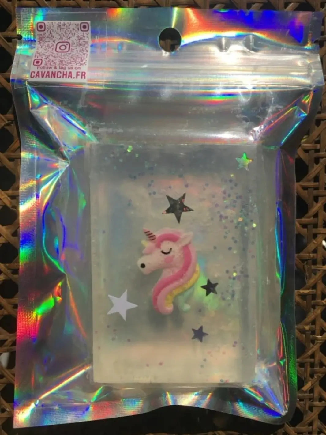 A sealed holographic pouch contains a transparent bar of Cavancha Magic Glitter Soap - Fairy Tales with an embedded pastel pink unicorn head surrounded by star shapes | Twentyseven Toronto