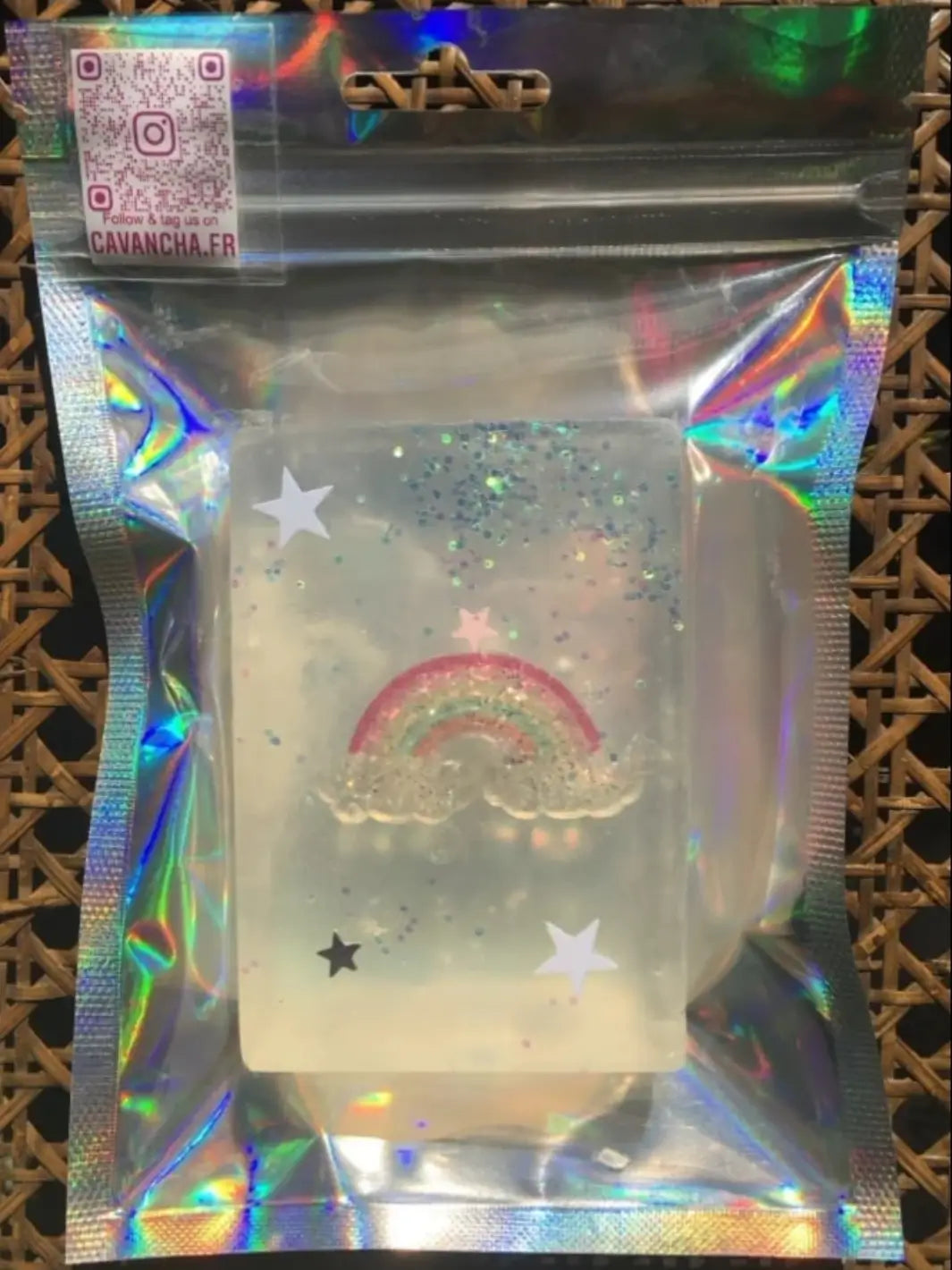 A single bar of clear Cavancha Magic Glitter Soap - Fairy Tales is sealed in a shiny pouch, highlighting an embedded rainbow with white clouds at its base | Twentyseven Toronto