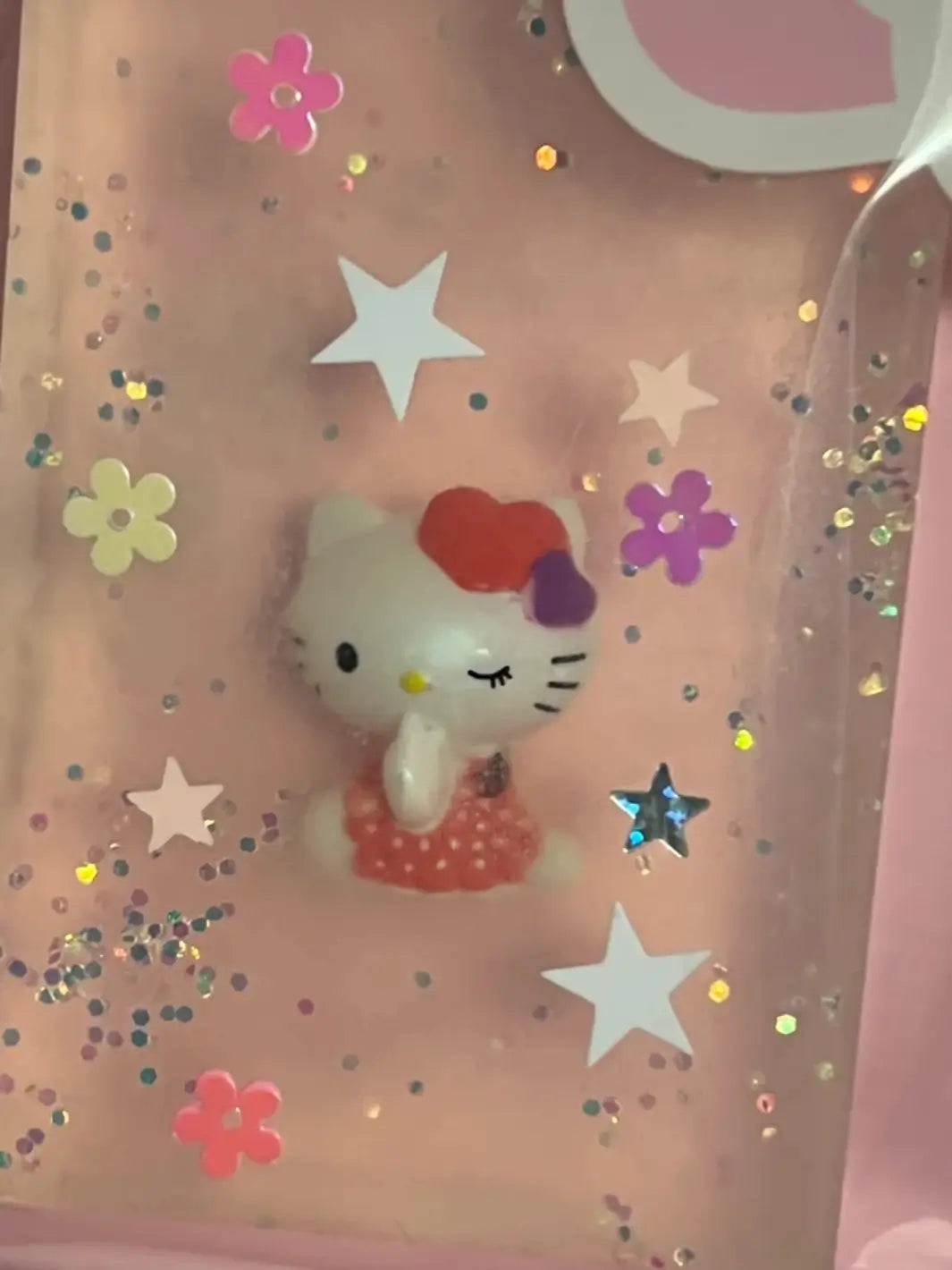 A close-up shot focuses on a transparent bar of Cavancha Magic Glitter Soap - Hello Kitty surrounded by colorful star and flower glitter | Twentyseven Toronto
