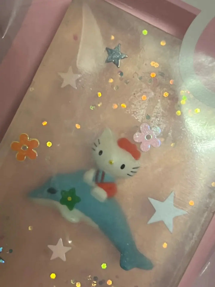 An angled close-up view highlights a bar of clear Cavancha Magic Glitter Soap - Hello Kitty embedded with a unique toy figure riding a blue dolphin among star confetti | Twentyseven Toronto