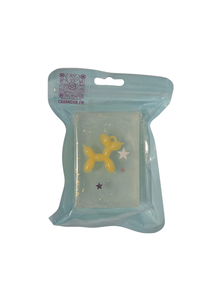 A clear bar of Cavancha Magic Glitter Soap - Jeff, containing a small yellow balloon dog charm and embedded star glitter, packaged inside a light blue pouch | Twentyseven Toronto