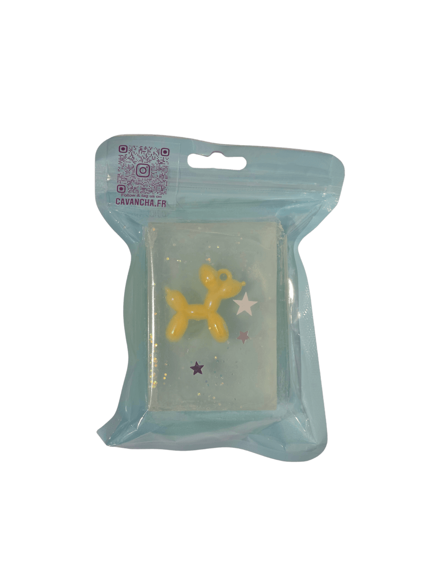 A clear bar of Cavancha Magic Glitter Soap - Jeff, containing a small yellow balloon dog charm and embedded star glitter, packaged inside a light blue pouch | Twentyseven Toronto