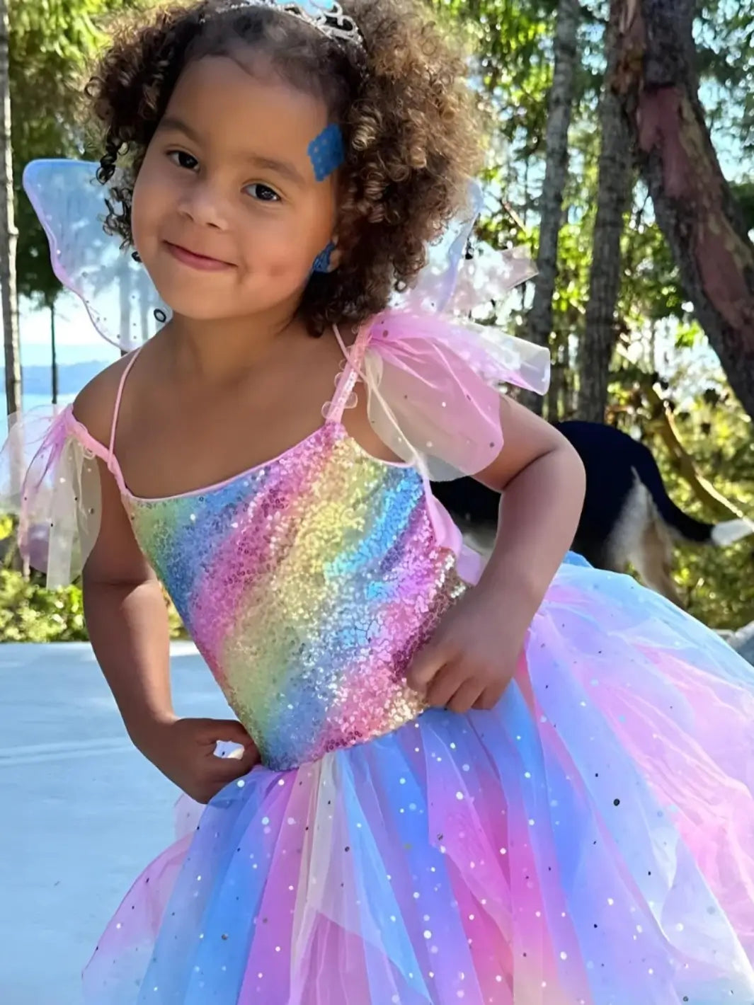 A young girl in a rainbow fairy costume smiles while wearing a NATPAT Magic Patch: Natural Bug Bite, Itch Relief Stickers on her temple | Twentyseven Toronto