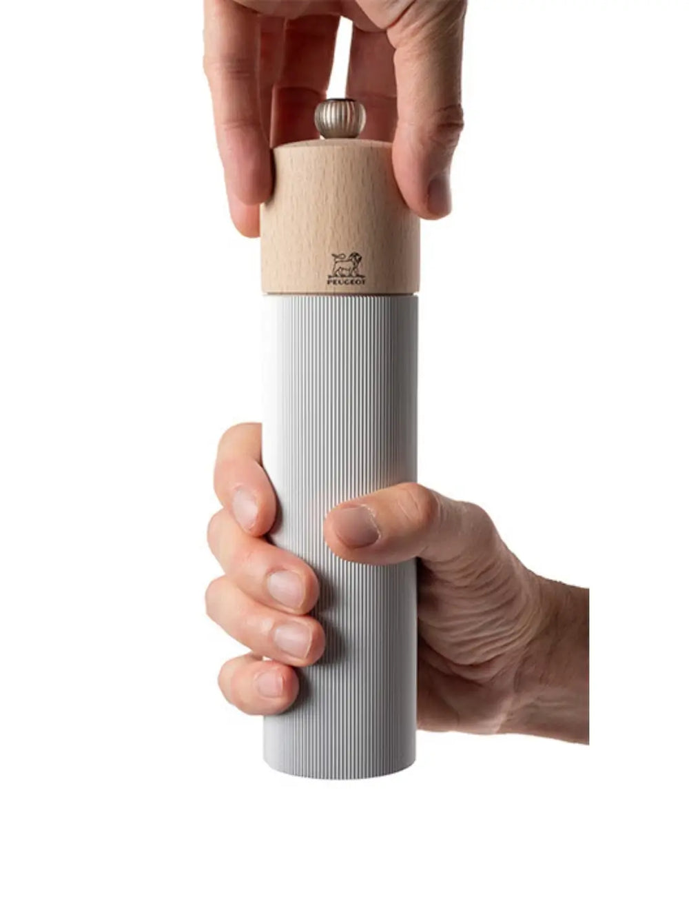 Hand holding white Line Manual Salt Mill grinder in Aluminum Natural with wooden top from Peugeot on a white background | Twentyseven Toronto