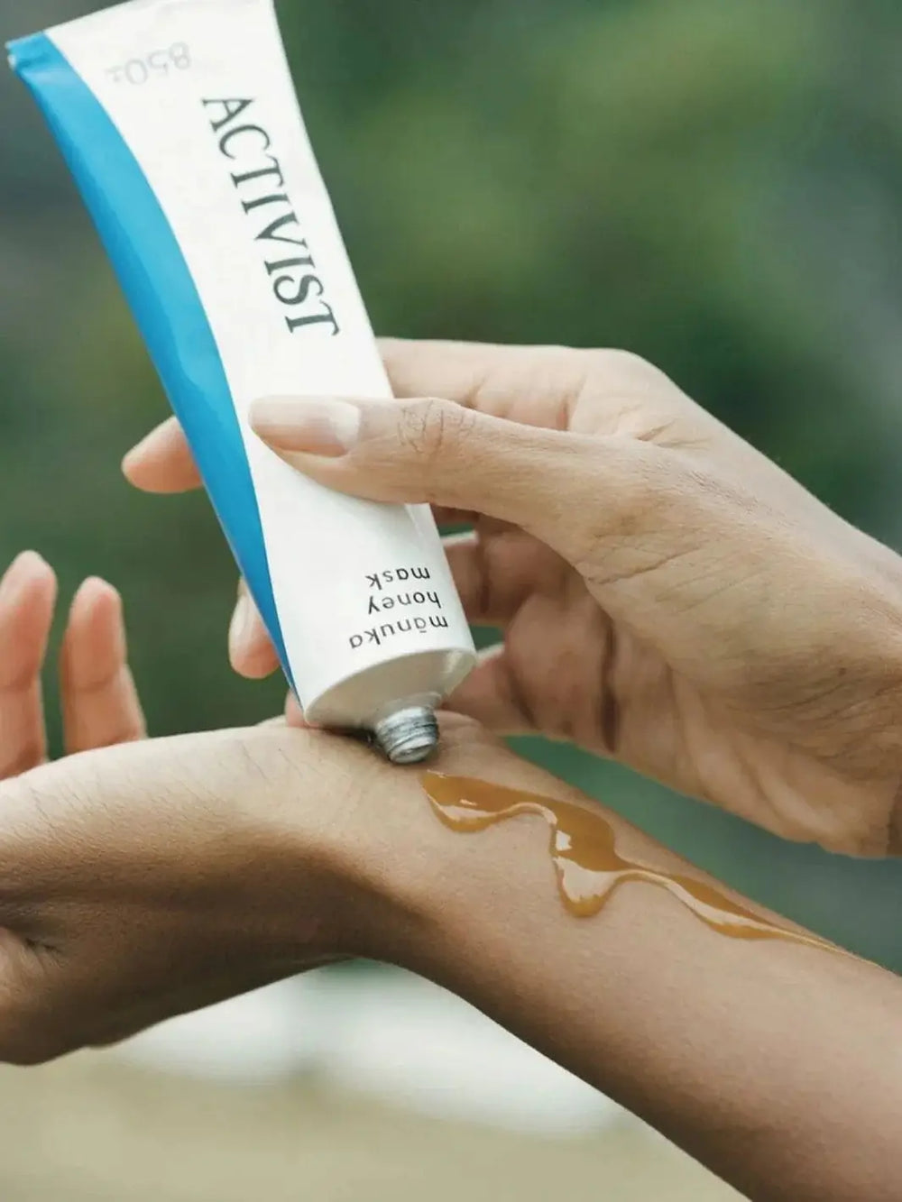 A thick, golden layer of the Activist Manuka Mānuka Honey Mask from its white and blue tube directly onto a person's inner wrist | Twentyseven Toronto