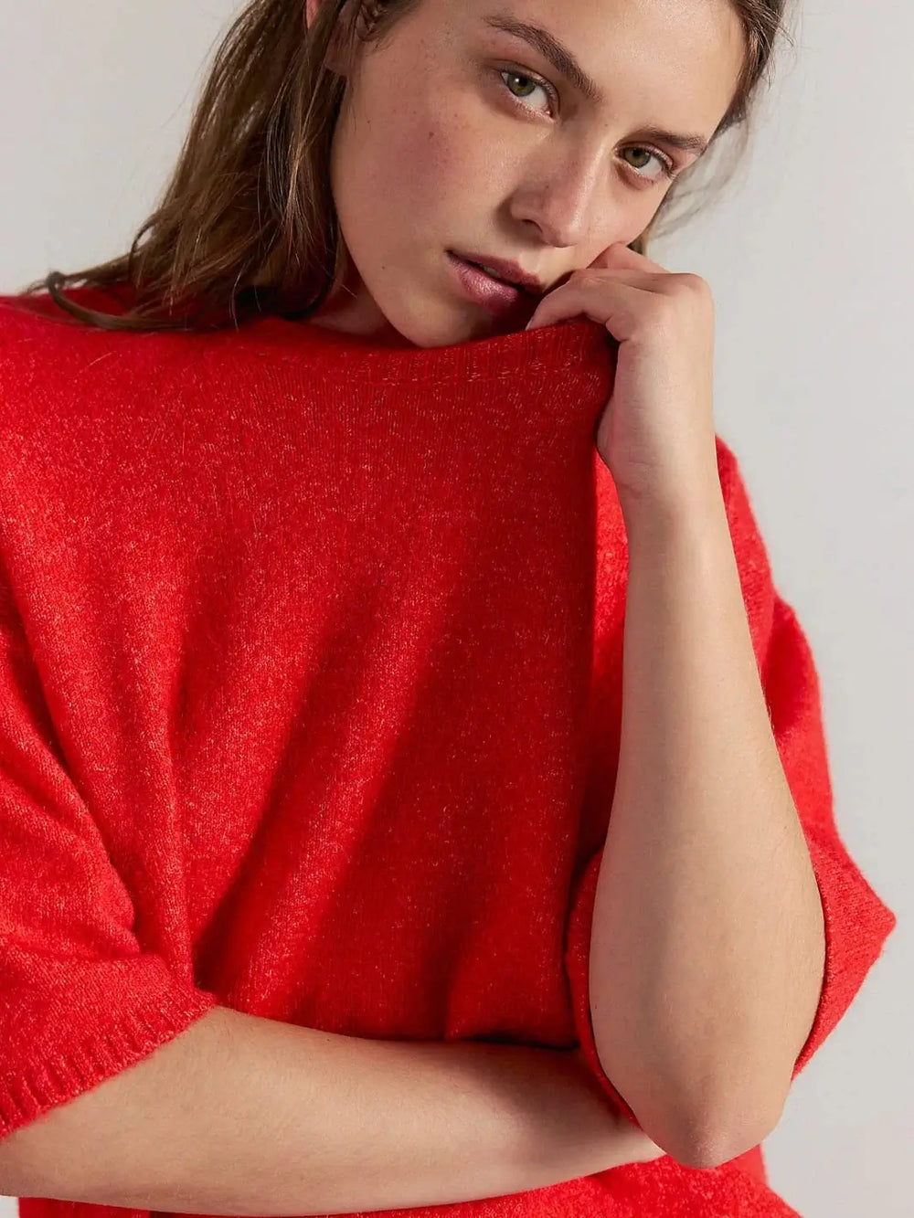 A close-up front view captures a model resting her chin on her hand, highlighting the soft knit texture and ribbed crew neckline of the Free People Margot SoftSpun Sweater Tee in Cherry Pop Melange | Twentyseven Toronto