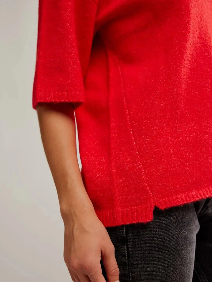 A detailed side close-up focuses on the ribbed knit cuff and small side-slit hem detail of the bright red Free People Margot SoftSpun Sweater Tee in Cherry Pop Melange | Twentyseven Toronto