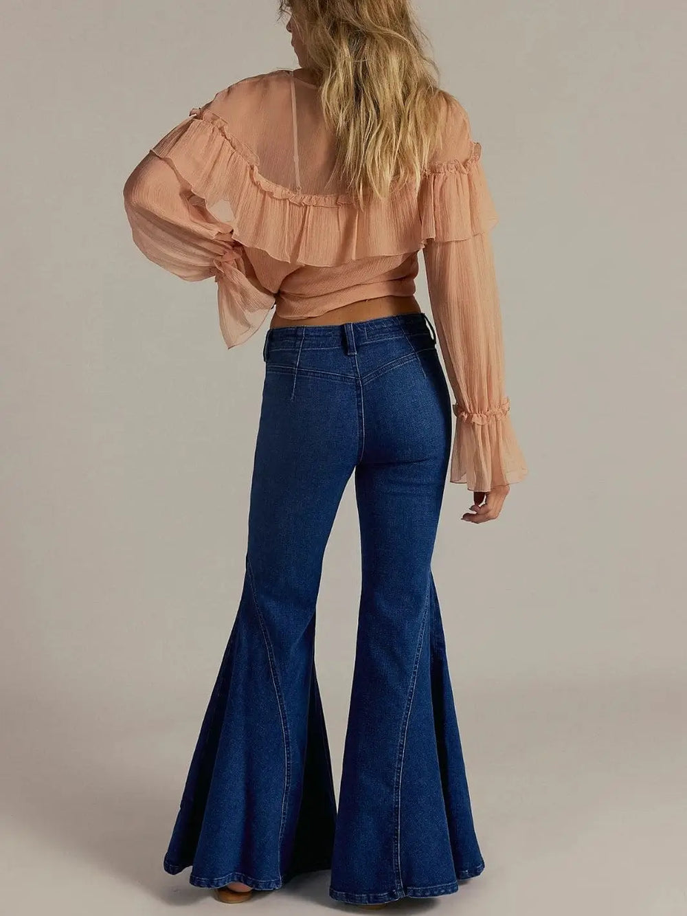 A rear view captures the full length and dramatic volume of the flared legs on the Free People Marque Flare Jeans - Kora | Twentyseven Toronto