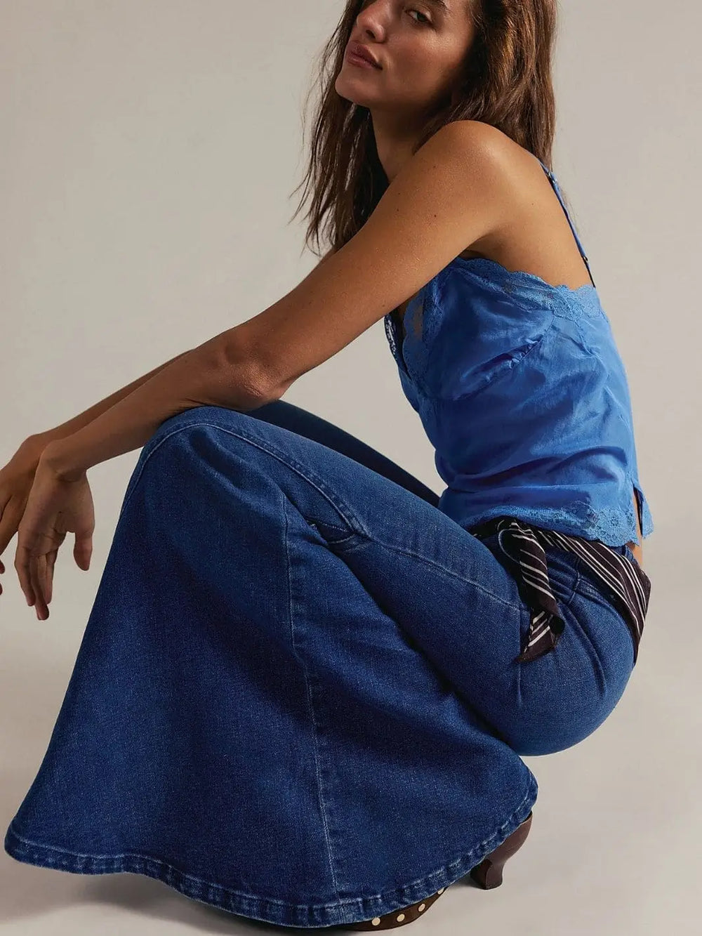 A model squats down to showcase the dramatic flare and deep indigo wash of the Free People Marque Flare Jeans - Kora | Twentyseven Toronto