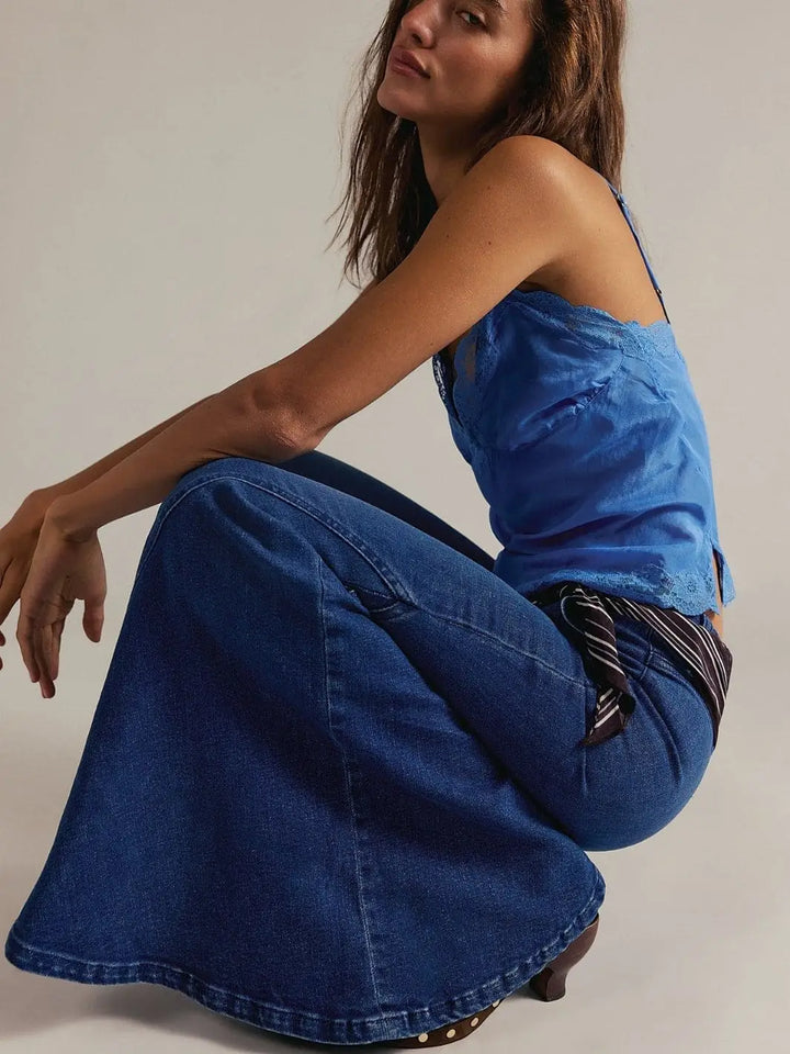 A model squats down to showcase the dramatic flare and deep indigo wash of the Free People Marque Flare Jeans - Kora | Twentyseven Toronto