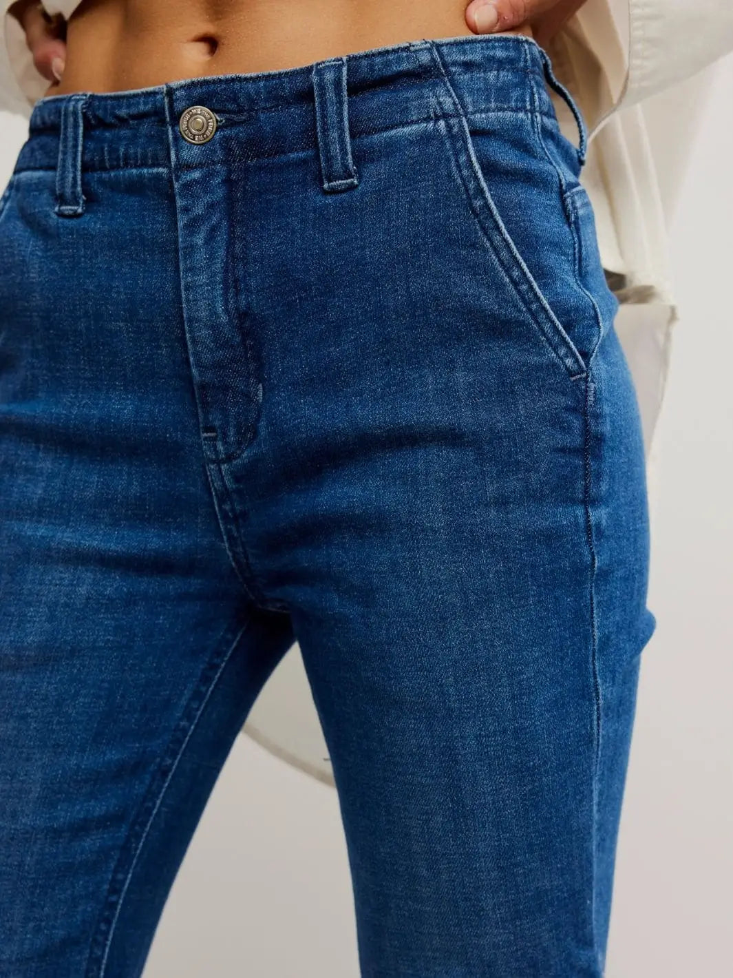 A close-up shot focuses on the single-button closure, classic belt loops, and subtle grain texture of the Free People Marque Flare Jeans - Kora | Twentyseven Toronto