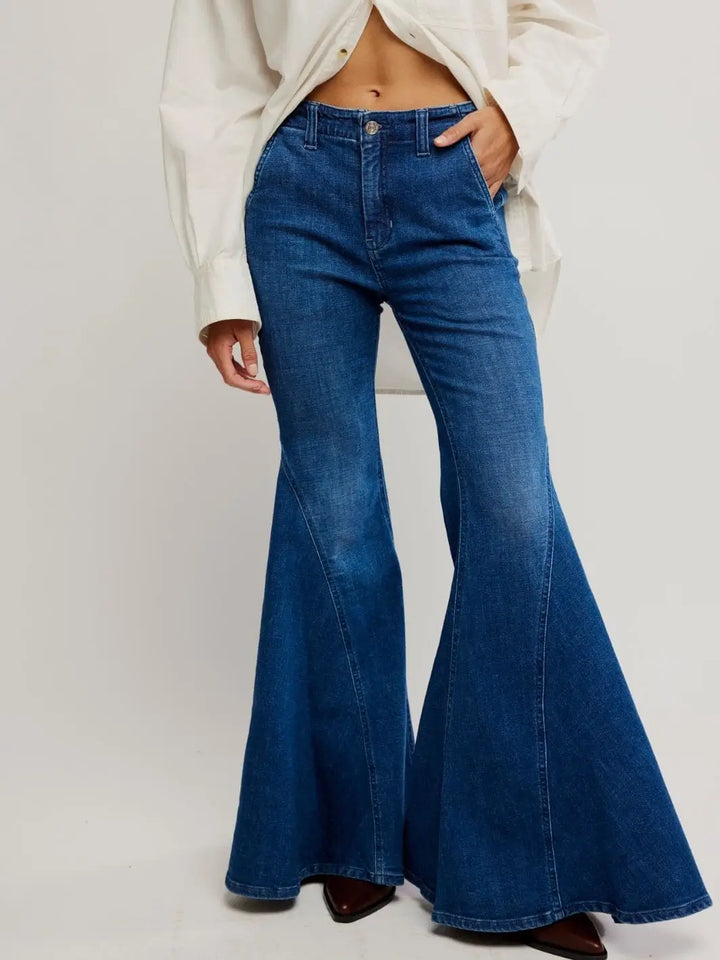 A model stands from the front with one hand in her pocket, showcasing the dramatic bell-bottom silhouette of the Free People Marque Flare Jeans - Kora | Twentyseven Toronto