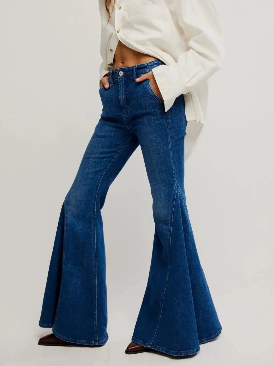 A three-quarter studio shot captures the distinct side-seam detailing and flowing length of the Free People Marque Flare Jeans - Kora | Twentyseven Toronto