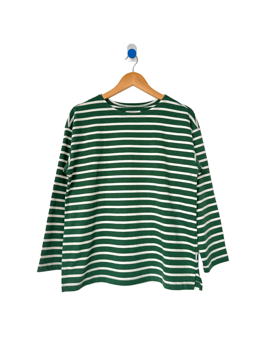 Marseille Top in White Stripe on Pine hanging on a wooden hanger, featuring green and white Breton stripes, a round neckline and relaxed long sleeves | Twentyseven Toronto