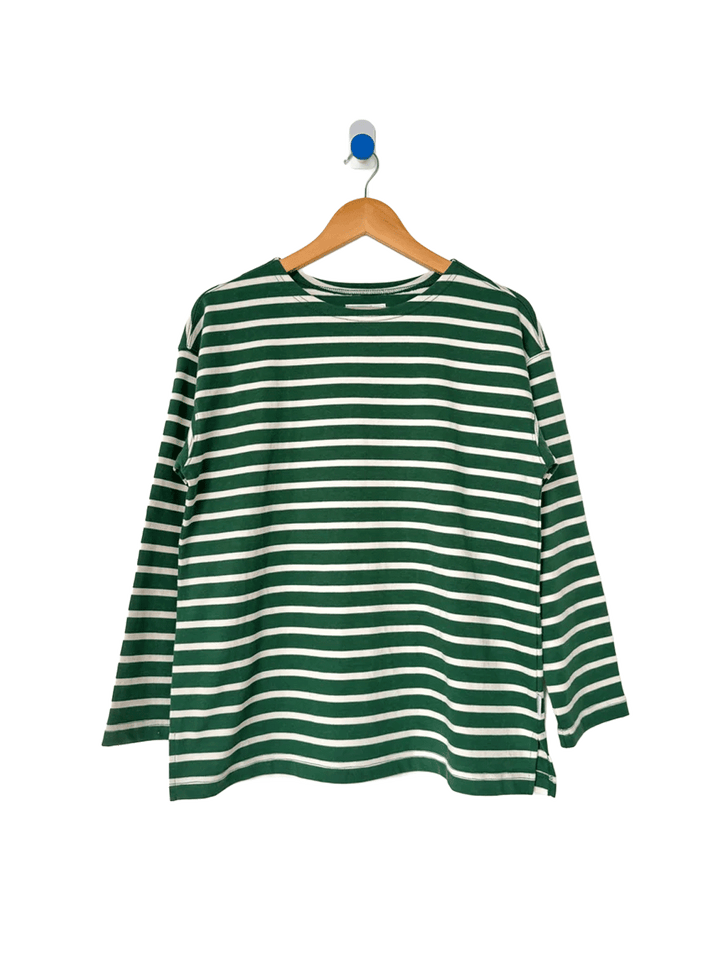 Marseille Top in White Stripe on Pine hanging on a wooden hanger, featuring green and white Breton stripes, a round neckline and relaxed long sleeves | Twentyseven Toronto