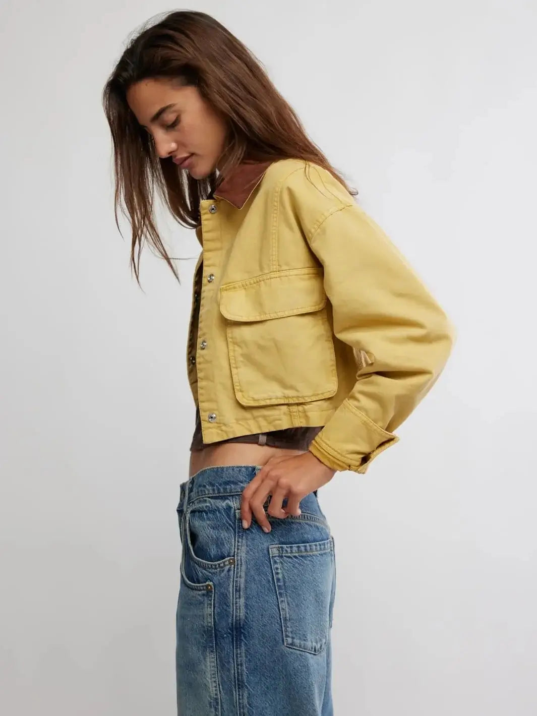 A side profile view emphasizes the raw cropped hemline, long sleeves, and casual silhouette of the Free People Martha Workwear Applique Jacket in Rattan | Twentyseven Toronto
