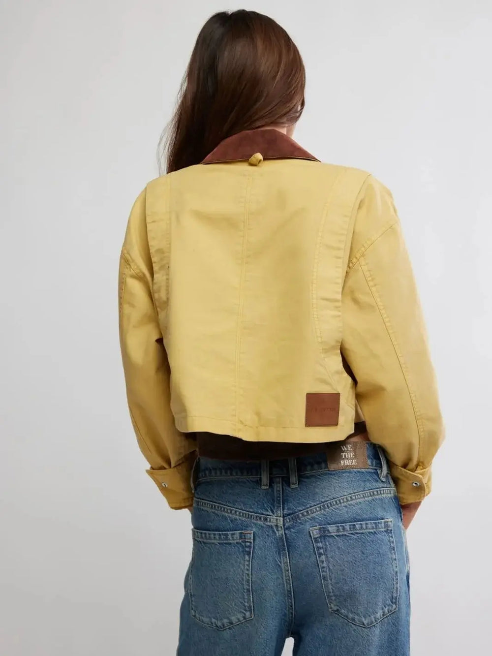 A direct rear view highlights the stitched back panels, brown contrast collar, and lower right leather logo patch of the cropped Free People Martha Workwear Applique Jacket in Rattan | Twentyseven Toronto