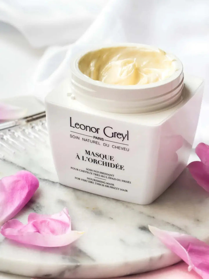 Leonor Greyl 'Masque à l’Orchidée' hair mask container with pink orchid petals on a marble surface | Twentyseven Toronto