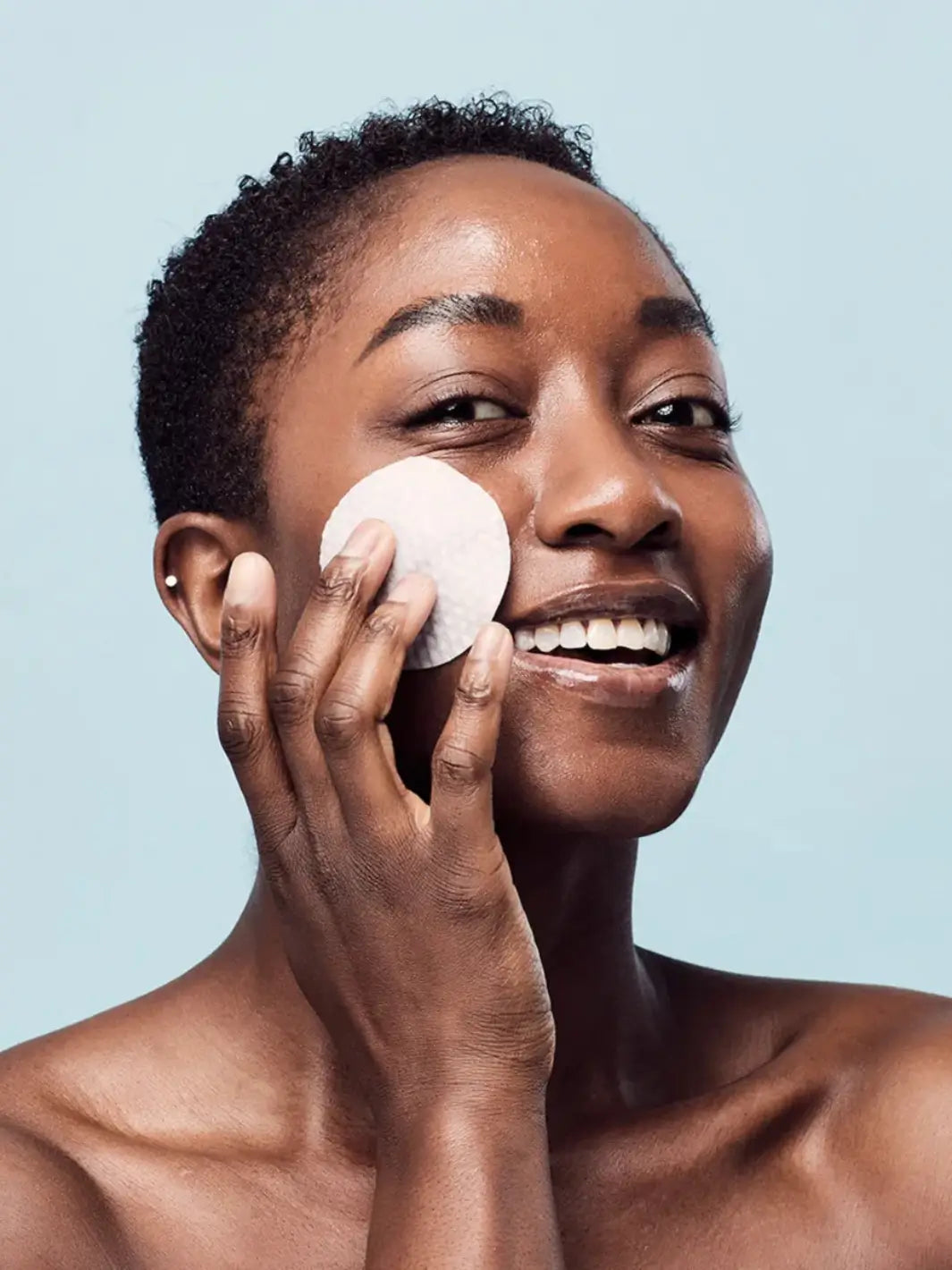 Woman applying Medicube Zero Pore Pad  to her face against a light blue background | Twentyseven Toronto
