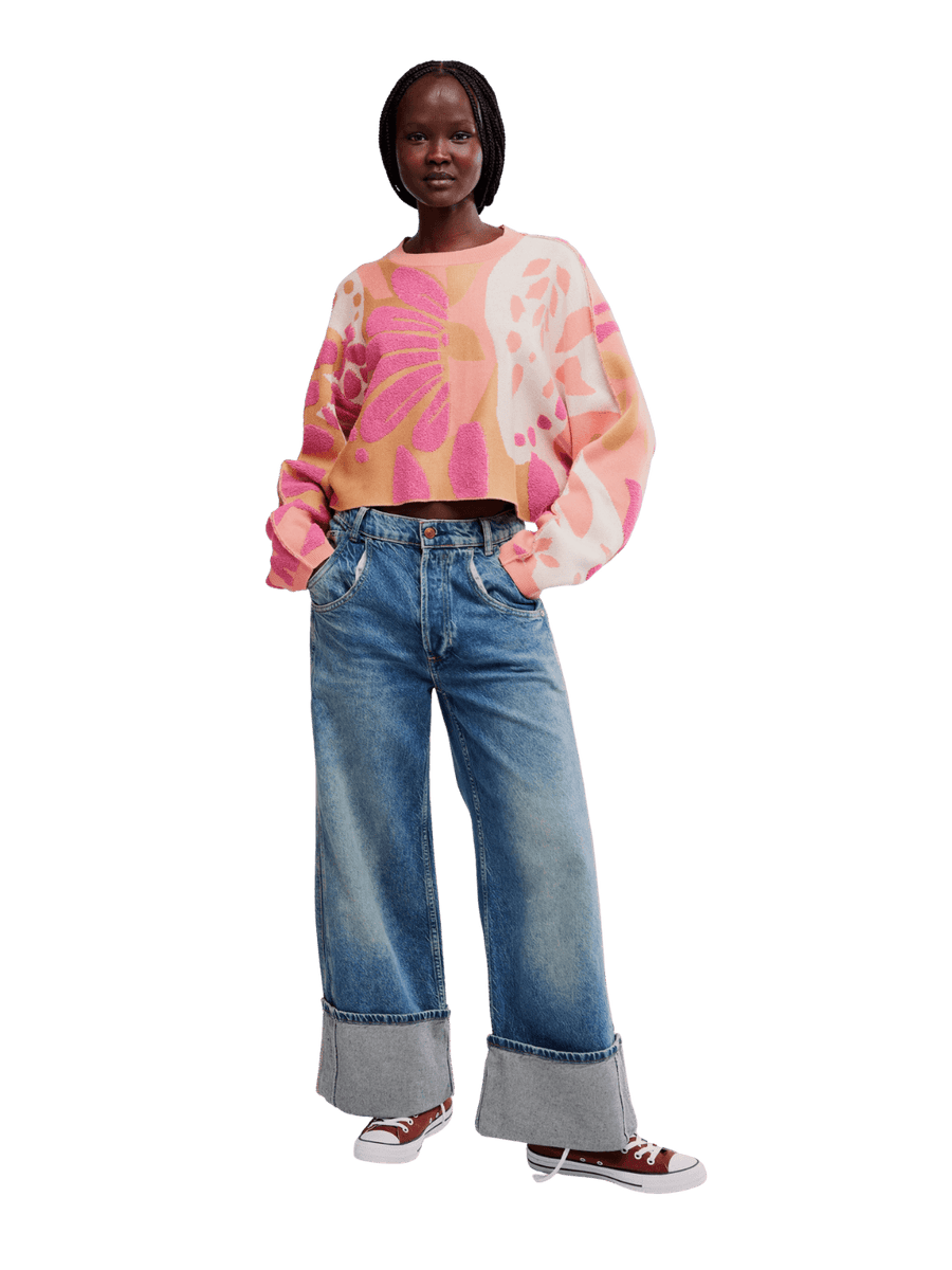 Full-length view of a model wearing the Free People Mia Pullover in Coral Kiss Combo styled with cuffed blue jeans and sneakers | Twentyseven
