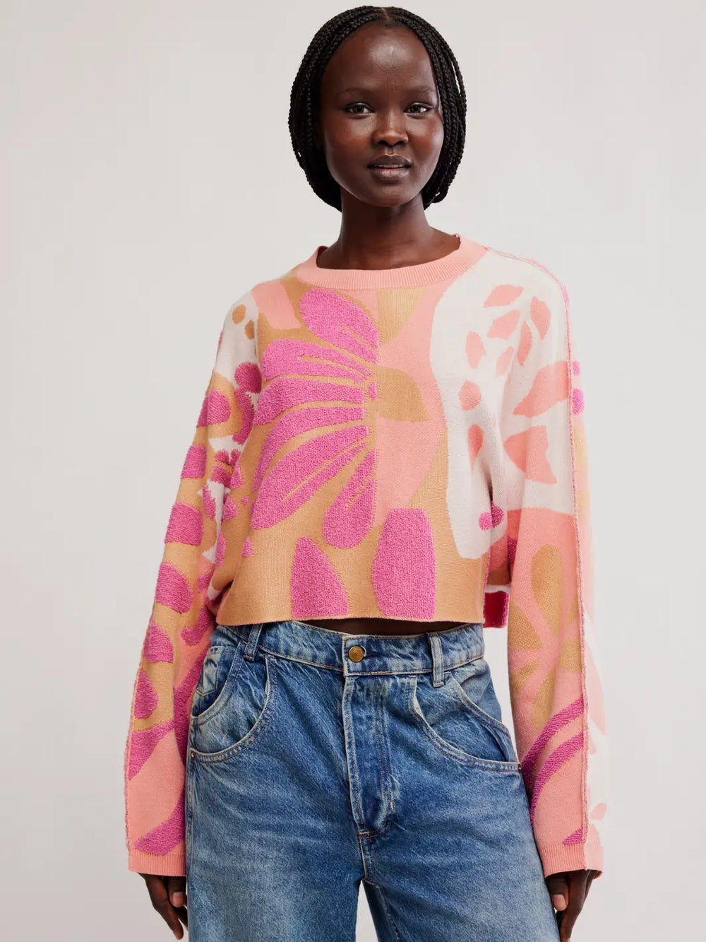 Front view of a model wearing the cropped, floral knit Free People Mia Pullover in Coral Kiss Combo paired with wide-leg jeans | Twentyseven