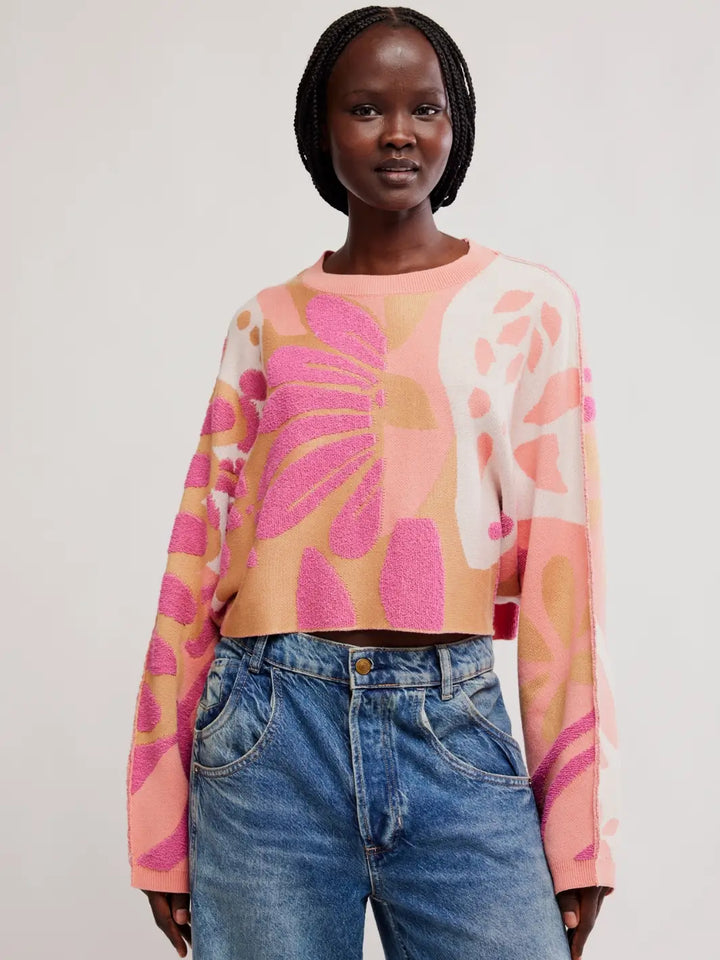 Front view of a model wearing the cropped, floral knit Free People Mia Pullover in Coral Kiss Combo paired with wide-leg jeans | Twentyseven