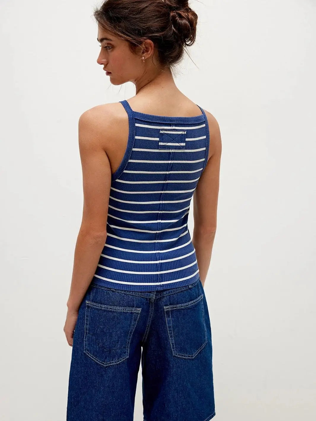 A rear view showcases the structured back seam and square-cut shoulders of the Free People Mia Striped Tank - Navy Combo styled with dark denim | Twentyseven Toronto