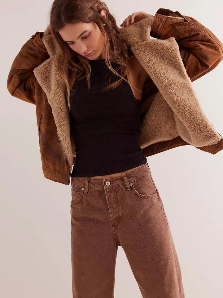 A model poses while putting on a brown fleece-lined jacket over the fitted Free People Mia Tank - Black and brown denim jeans | Twentyseven Toronto