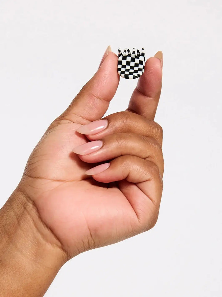 A hand with neutral-painted nails holds a single checkered hair clip from the CHUNKS Micro Claws in Geo set to show its tiny size | Twentyseven Toronto