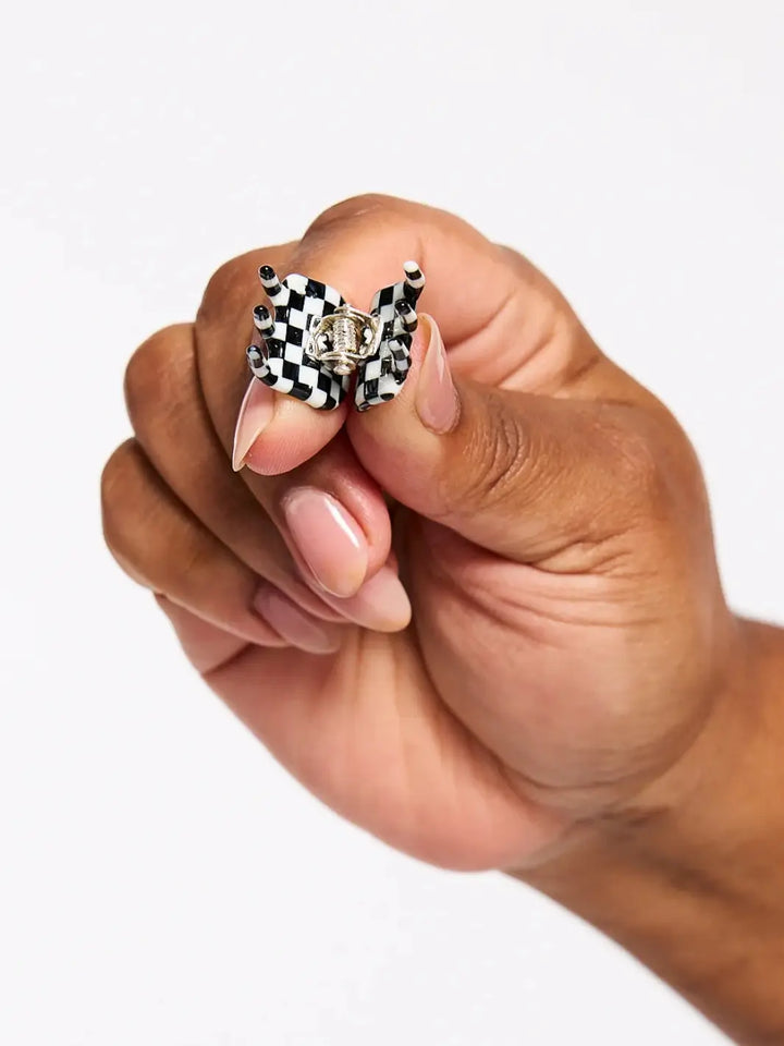 A close-up view shows a hand squeezing open a single black-and-white checkered claw clip from the CHUNKS Micro Claws in Geo set | Twentyseven Toronto