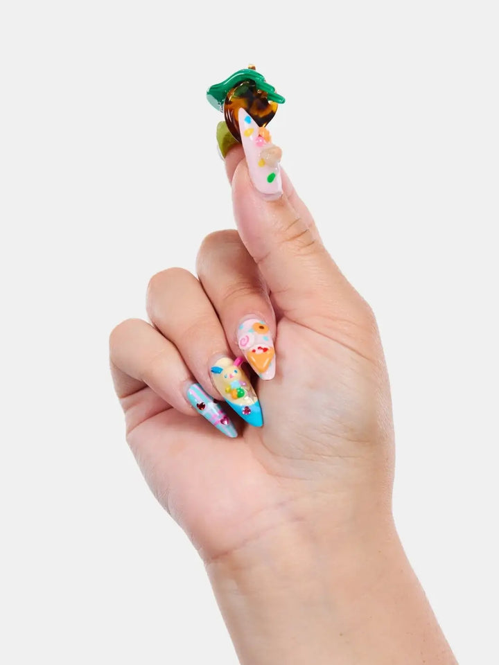 A hand with decorated acrylic nails pinches open a single green and tortoiseshell claw clip from the Chunks Hairclips Micro Claws in Hot Mama collection | Twentyseven Toronto