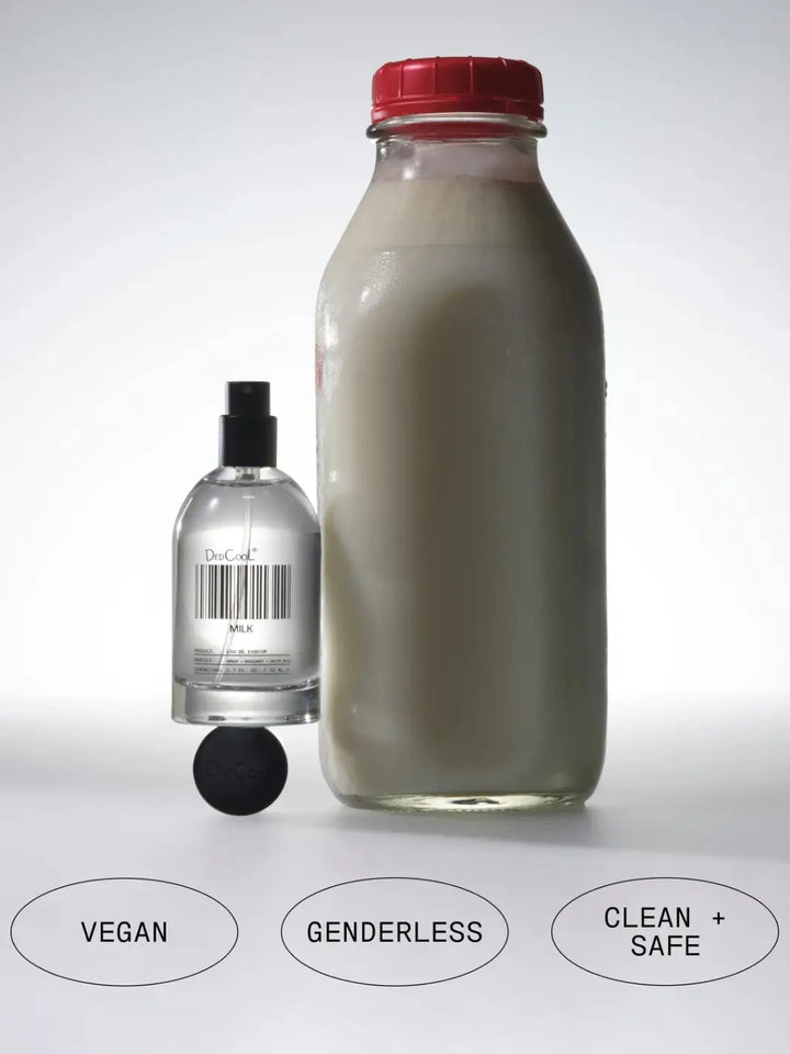 A bottle of Dedcool Milk Layering + Enhancer Fragrance Full Size 50ml resting next to a vintage glass milk bottle beneath labels reading "Vegan," "Genderless," and "Clean + Safe" | Twentyseven Toronto