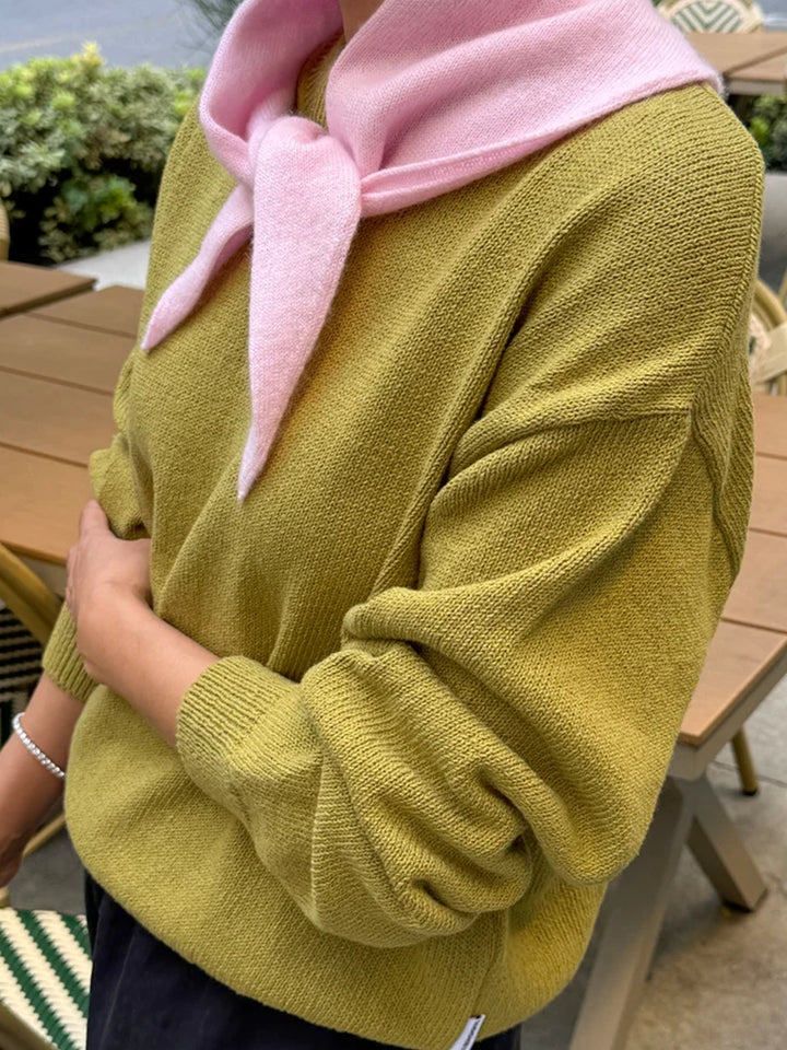 Model wearing the Le Bon Shoppe Milo Cotton Sweater in Golden Olive with a pink sweater draped over the shoulders | Twentyseven Toronto