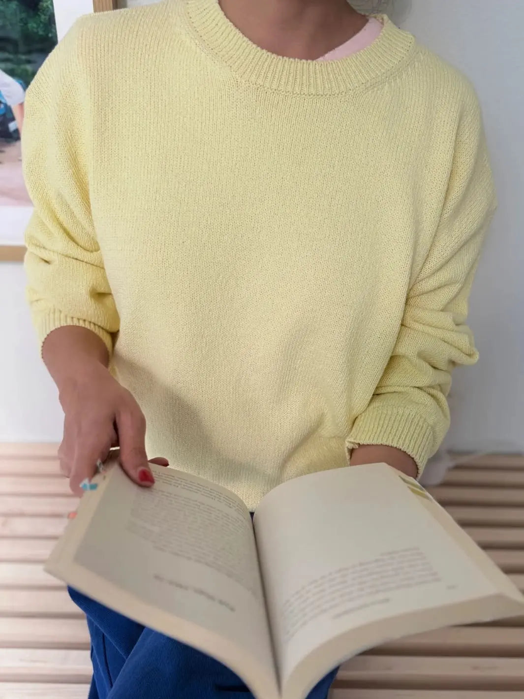 Person wearing a light yellow 'Milo Cotton Sweater' in 'Lemonade' sweater from Le Bon Shoppe holding an open book | Twentyseven Toronto