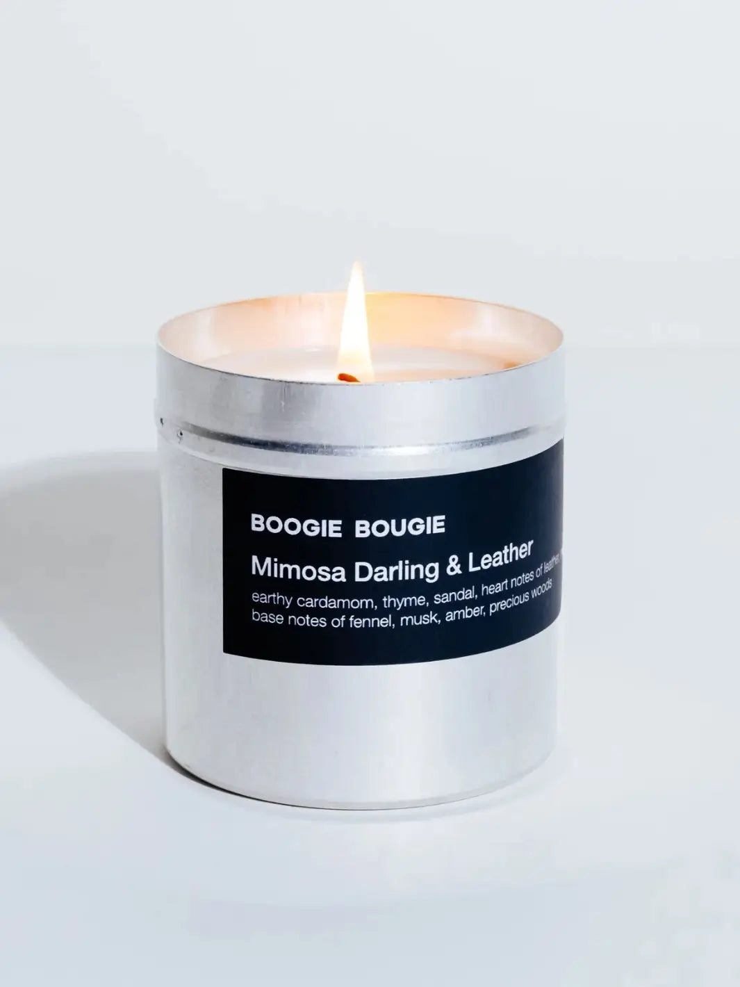 Lit Mimosa and Darling Leather candle in a silver container with a black 'Boogie Bougie' label on a white background | Twentyseven Toronto