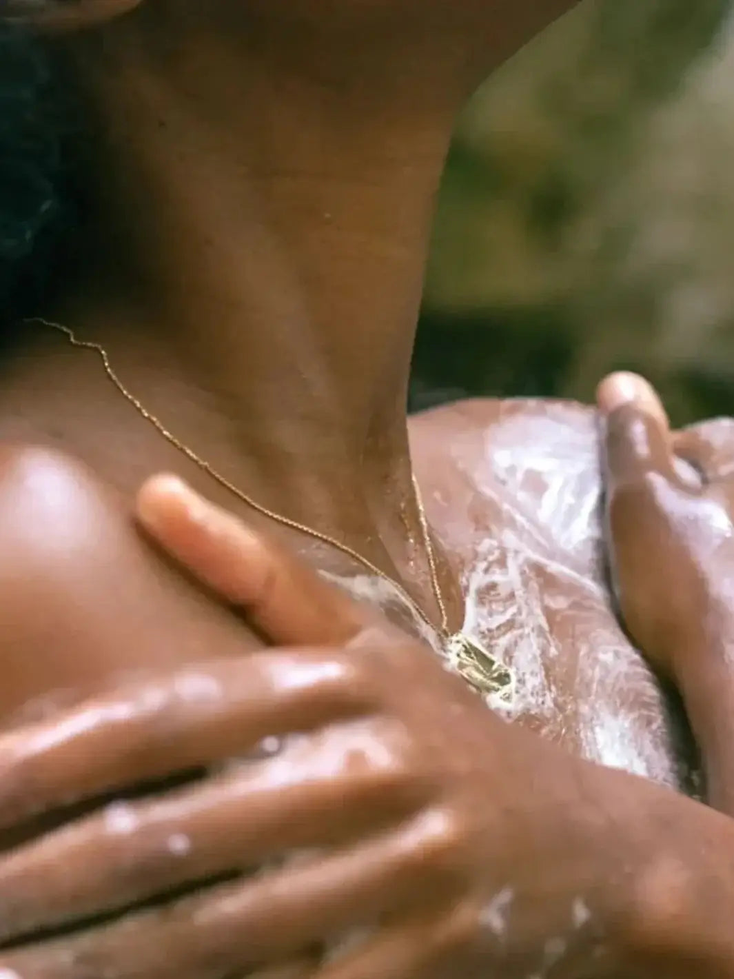 A close-up shot shows a person with a gold necklace lathering their chest and shoulders with the white, sudsy foam of Bathing Culture Mind & Body Wash - Meadow Vision | Twentyseven Toronto