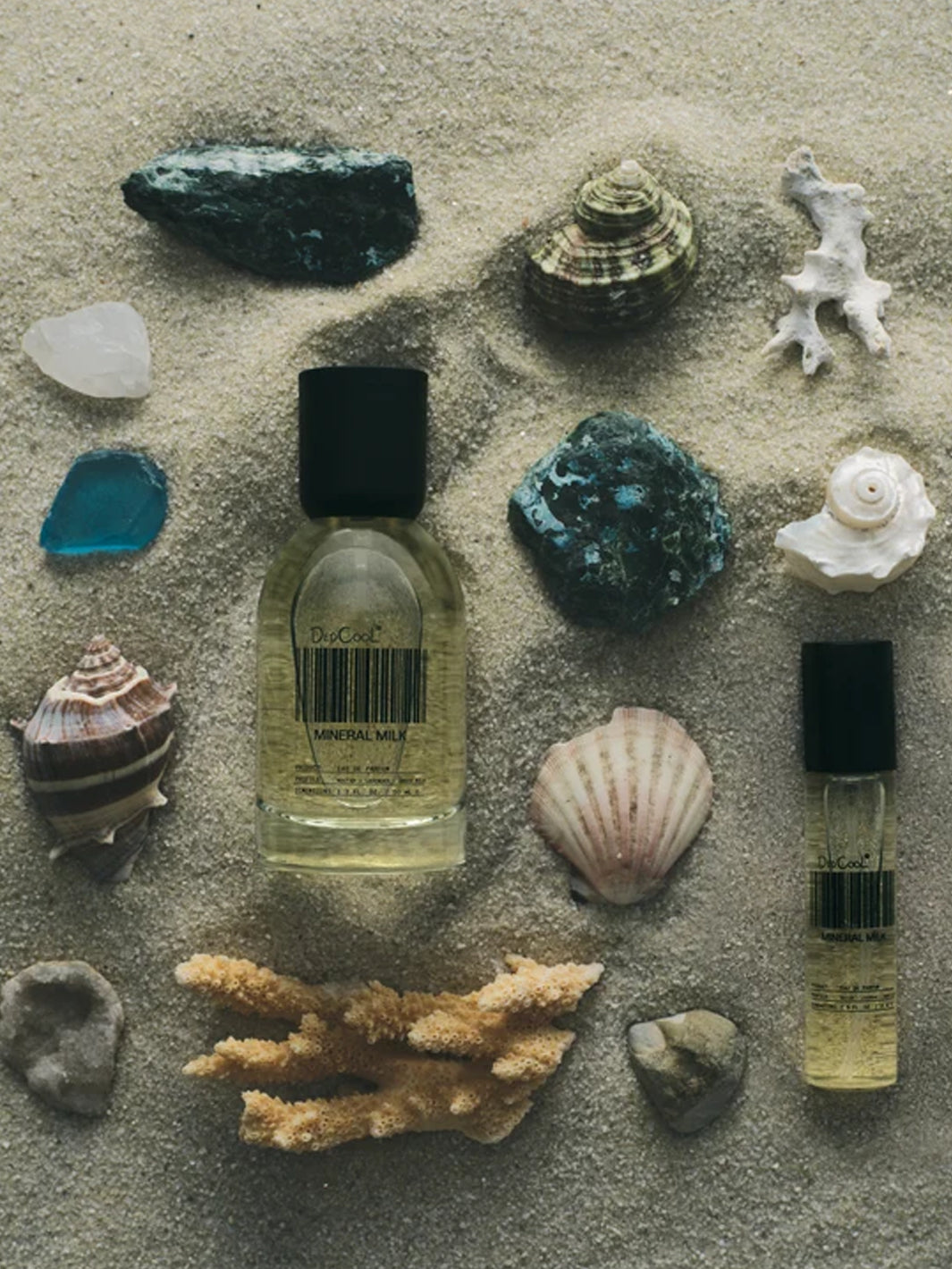 DedCool Mineral Milk Eau de Parfum styled on sand with seashells, coral, and stones | Twentyseven Toronto