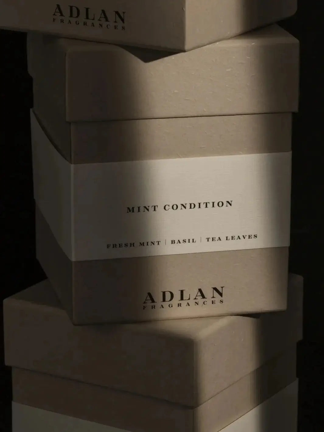 A stacked pile of grey Adlan Fragrances Mint Condition - Petite product packaging boxes | Twentyseven Toronto