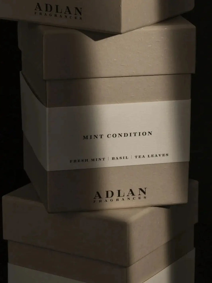 A stacked pile of grey Adlan Fragrances Mint Condition - Petite product packaging boxes | Twentyseven Toronto