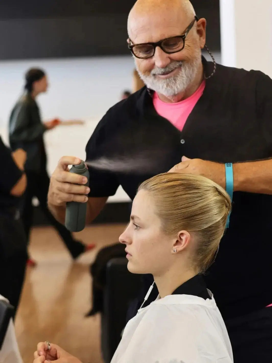 A behind-the-scenes photo captures stylist Sam McKnight applying a fine mist to secure a model's sleek updo using the Hair by Sam McKnight Modern Hairspray | Twentyseven Toronto