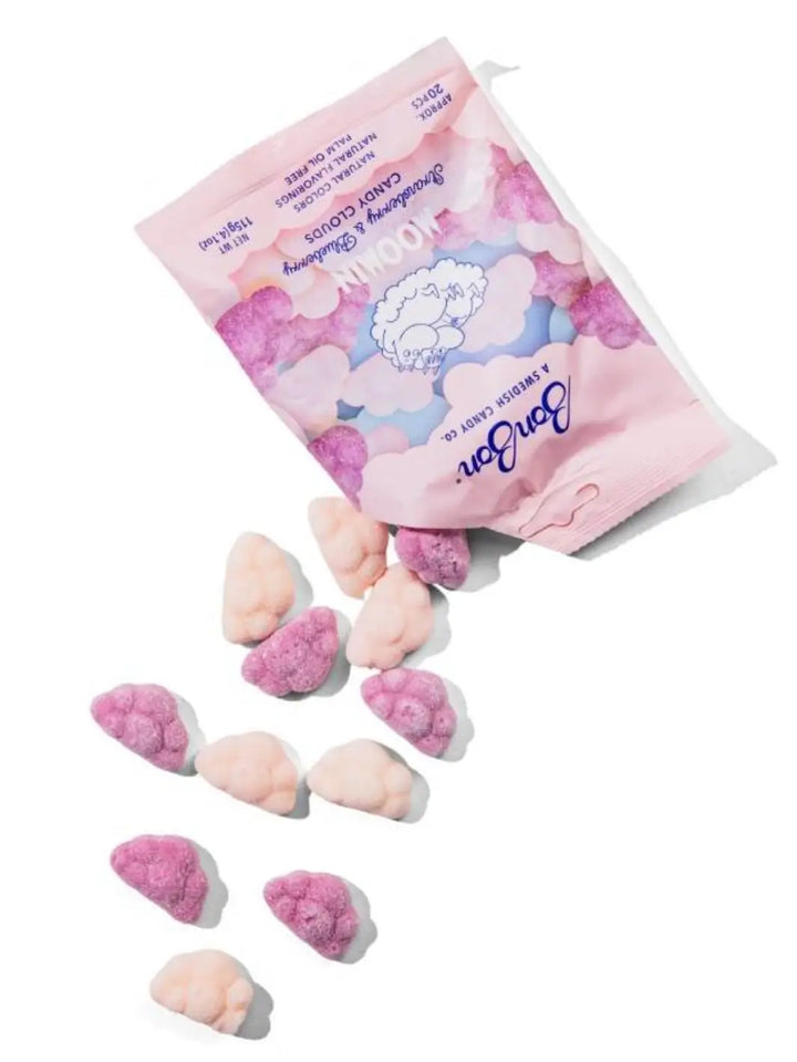 Several pieces of pink and purple cloud-shaped gummies spill out from an open pink pouch of BonBon Swedish Candy Moomin Candy Clouds onto a white background | Twentyseven Toronto