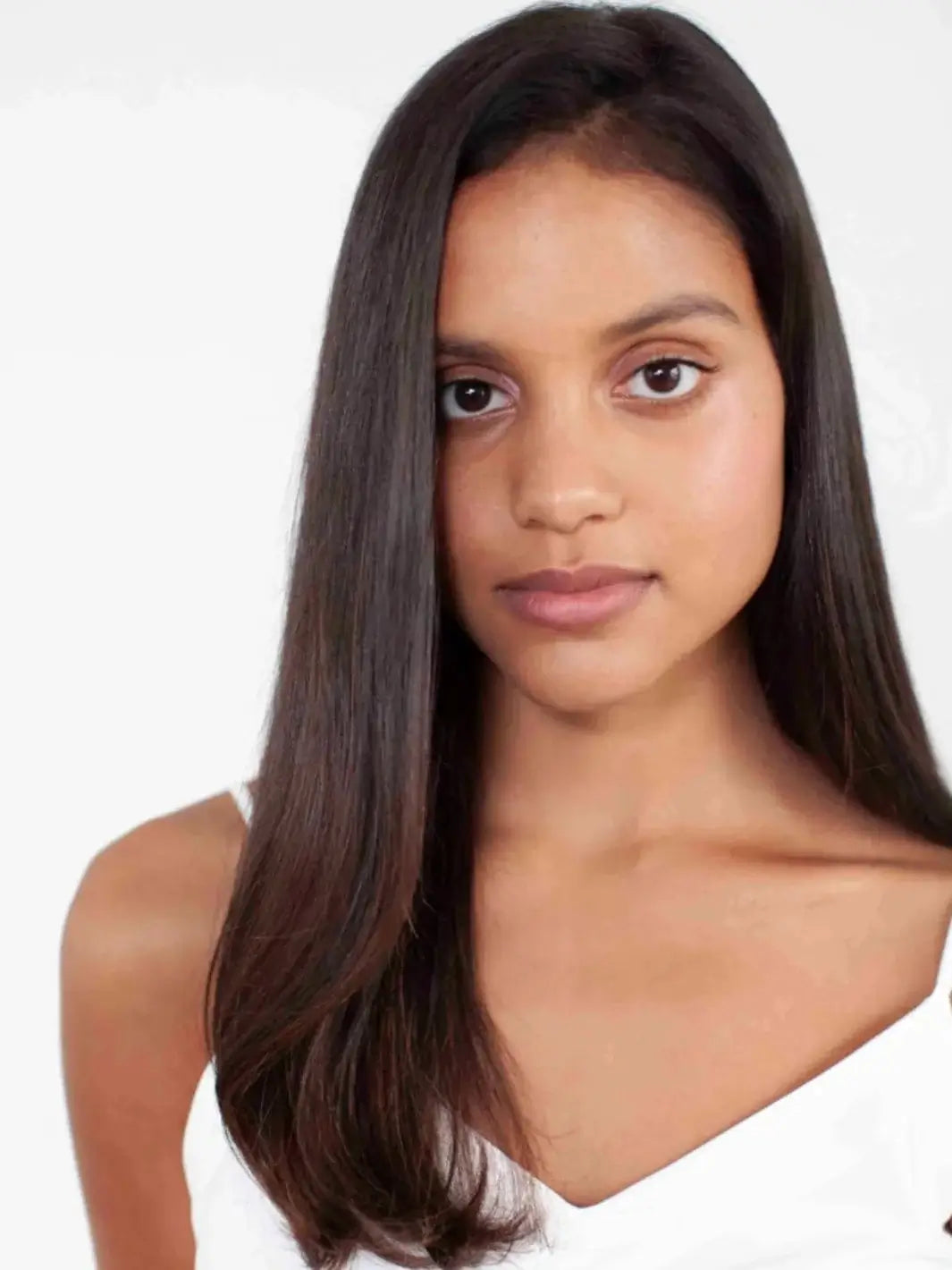 A close-up portrait of a model showcasing smooth, frizz-free brunette hair styled with R+Co MOON LANDING Anti-Humidity Spray | Twentyseven Toronto