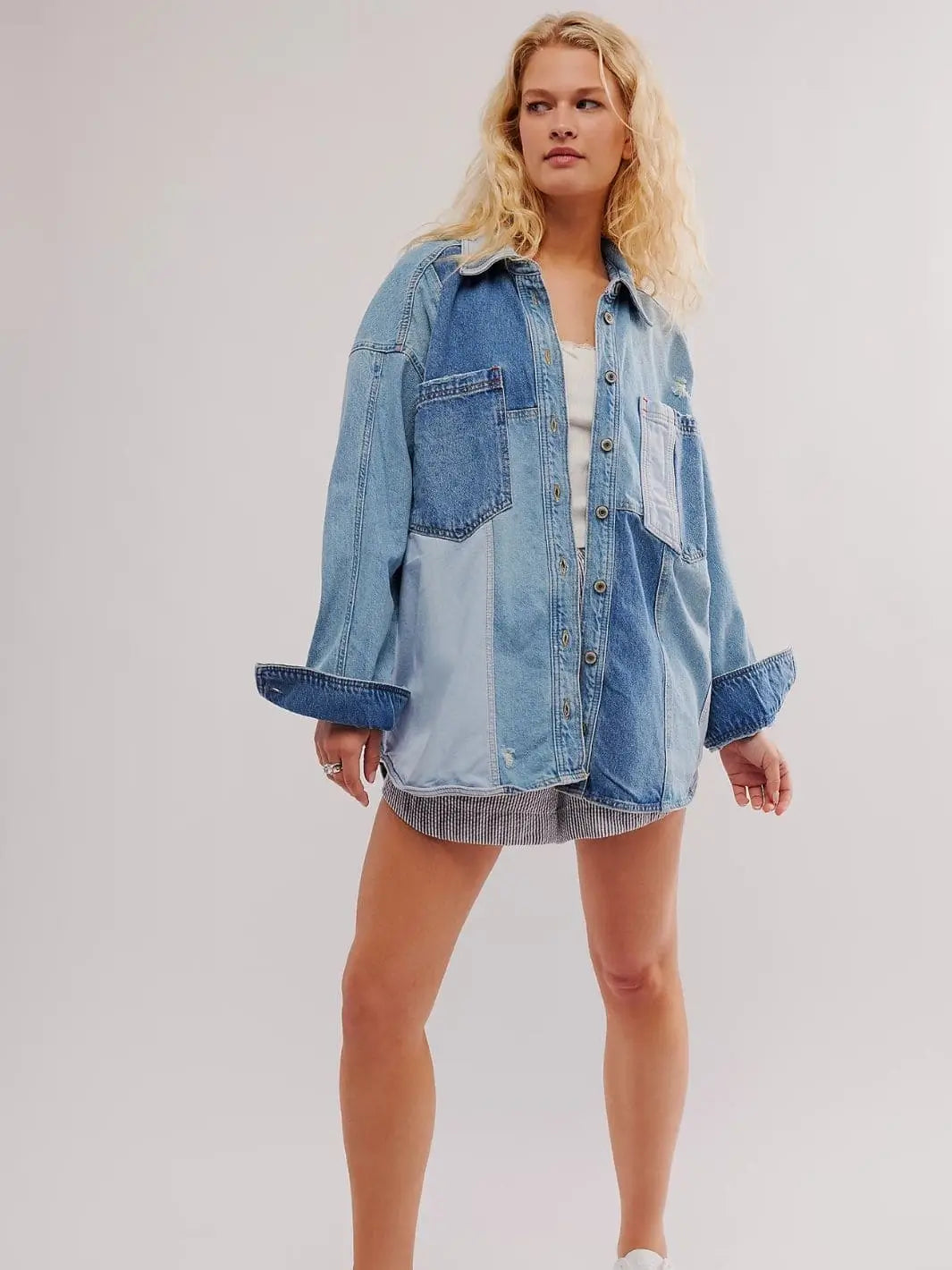 A full-length shot of a model standing against a white backdrop wearing the oversized Free People We The Free Mountain Roads Shirt - Mixed with striped shorts | Twentyseven Toronto